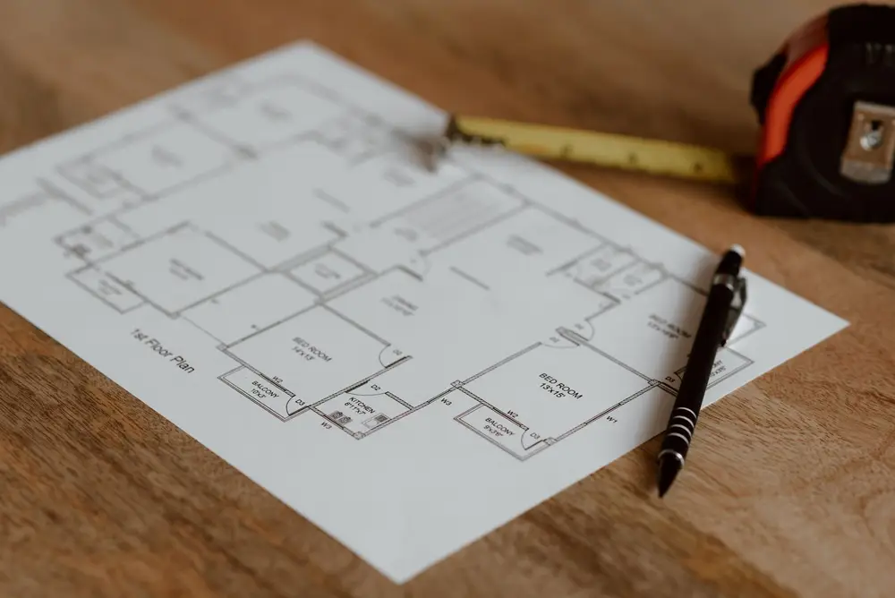 Floor plan on a desk with a tape measure and pen